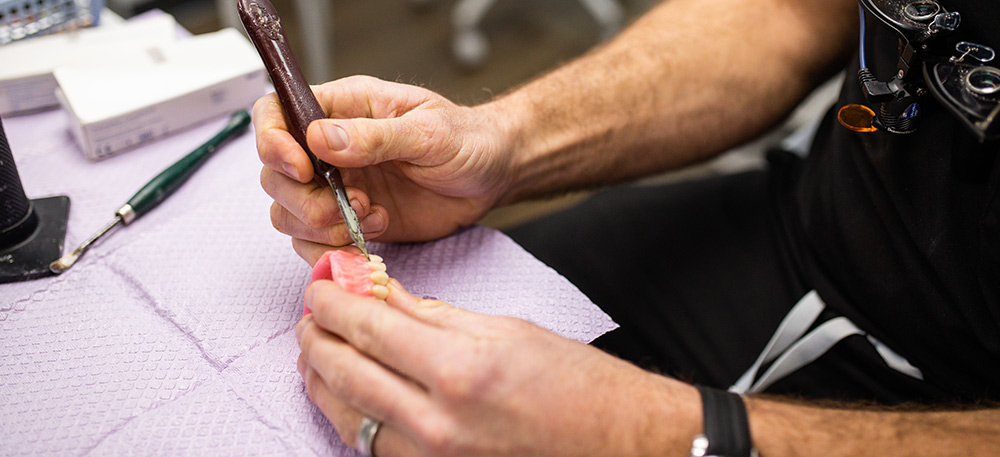 Dentist shaping and adjusting custom dentures during the fabrication process